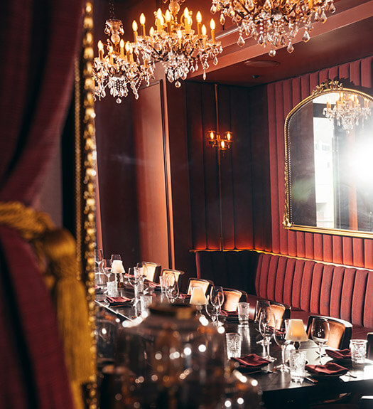 Dining area with plush booth seating, chandeliers, and an ornate mirror