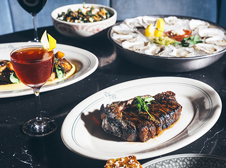 Plated steak dinner with cocktail, oysters, and salad