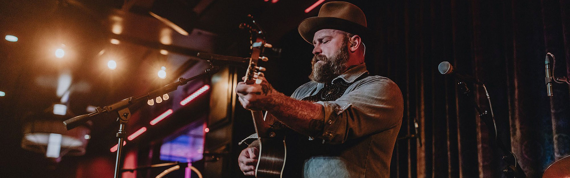 Man playing guitar on a stage in a hat